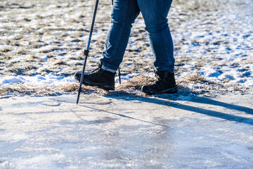 Person walking on ice with spikes and walking poles.