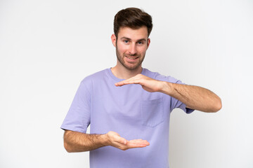 Young caucasian man isolated on white background holding copyspace imaginary on the palm to insert...
