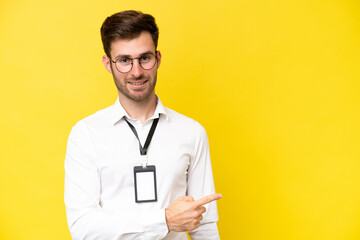 Young caucasian with ID card isolated on yellow background pointing to the side to present a product