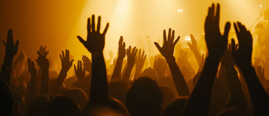 A crowd bathed in concert glow, hands up in a unison of celebration and shared musical ecstasy