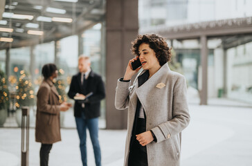 Professional woman on phone with colleagues discussing business outdoors.