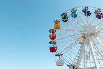 Old colorful ferris wheel on background of blue sky.