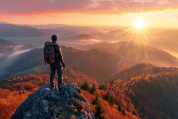 Sporty man admiring autumn sunset on mountain peak. - obrazy, fototapety, plakaty