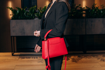 Close-up photo of a faceless girl with a red stylish bag in her hands