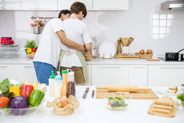 Young lgbtq Asian gay boyfriend hug partner in kitchen during cook