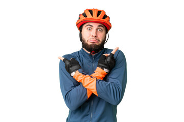 Young cyclist man over isolated chroma key background pointing to the laterals having doubts - obrazy, fototapety, plakaty