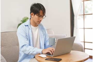 Business at home concept, Businessman drinking coffee in the morning and typing data on laptop