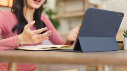 Obraz premium Young businesswoman explaining business project with partners while meeting in video call on tablet