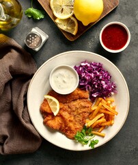 Pork schnitzel served with potato fries, red cabbage salad and sauce