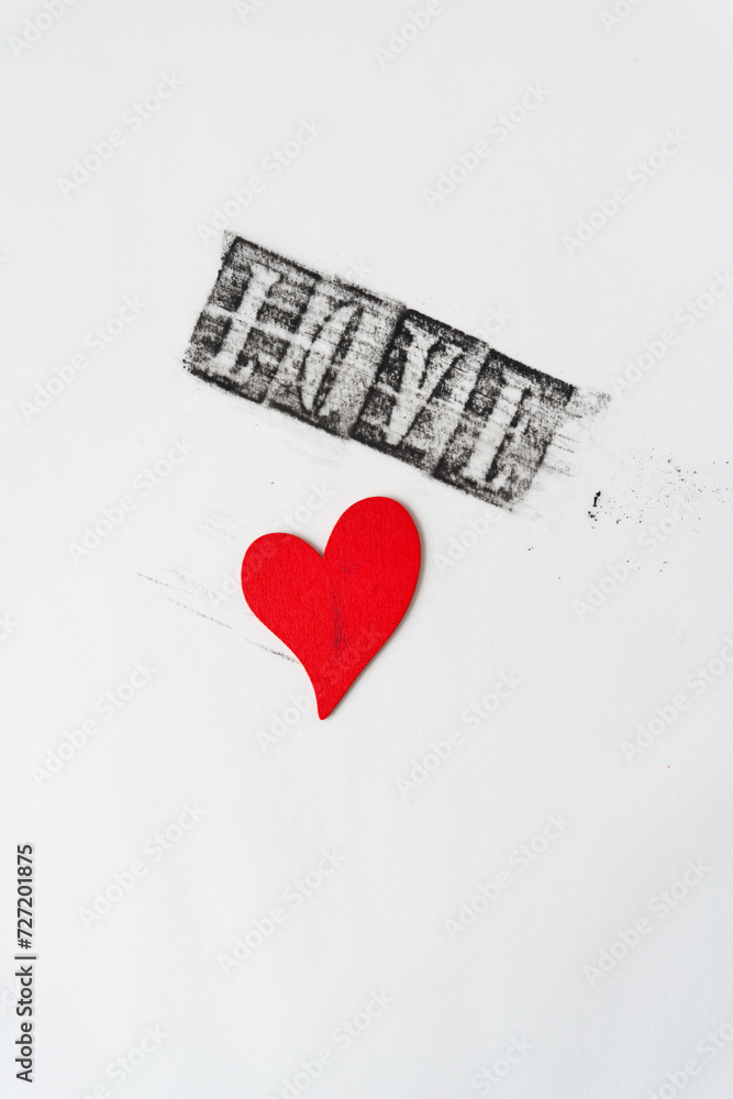 Sticker grungy stenciled word love and stained heart made of wood and painted red on blank paper