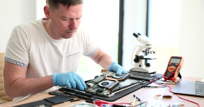 Engineer repairs laptop and disassembled computer parts. Electronic components of PC hard drive and processor motherboard