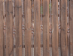 Fragment of a fence made of wooden boards and brown iron rods.