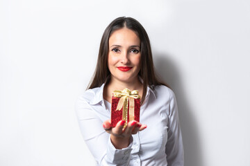 Attractive woman in white shirt holds gift box. Christmas or New year celebration concept.