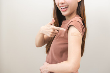 Obraz premium Healthcare of Covid-19, coronavirus vaccination, happy asian young woman hand pointing, showing at bandage, plaster on arm, getting vaccine immunity, giving injection influenza to protection pandemic.