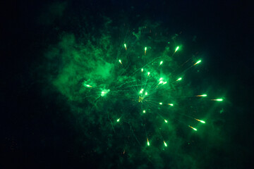 Burst of green fireworks at night - vibrant green streaks and sparks - smoke clouds - celebration,...