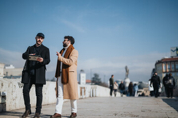 Two stylish men discussing business on a city bridge on a sunny day.