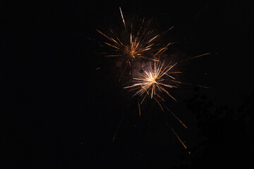 Fototapeta premium Burst of orange fireworks at night - vibrant streaks and sparks - smoke clouds - celebration, new years day, fourth of july, canada day. Taken in Toronto, Canada.