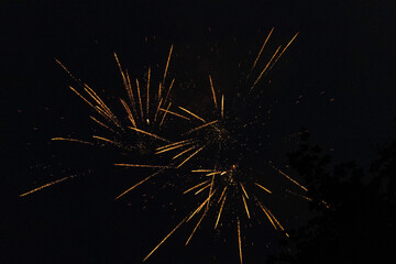 Burst of orange fireworks at night - vibrant orange streaks and sparks - smoke clouds -...