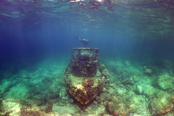 a small sunken ship and a diver on the island of Curacao
