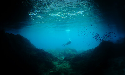 a diver at the entrance to a large cave on the island of Curacao