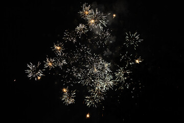 Bursts of white and yellow fireworks at night - vibrant streaks and sparks - smoke clouds - celebration, new years day, fourth of july, canada day. Taken in Toronto, Canada.