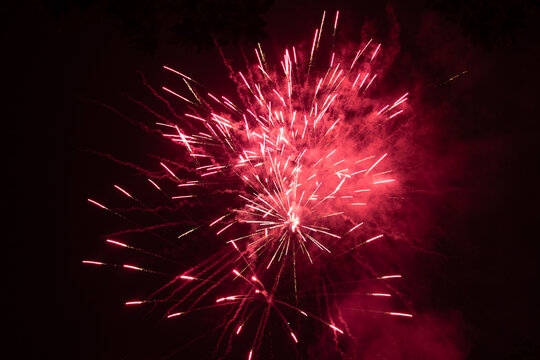 Burst of red fireworks at night - vibrant red streaks and sparks - smoke clouds - celebration, new years day, fourth of july, canada day. Taken in Toronto, Canada.