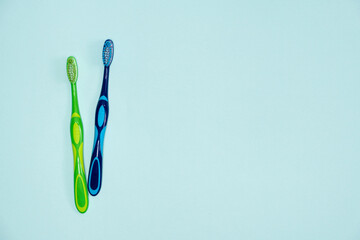 Two toothbrushes on a blue background, top view, space for text.