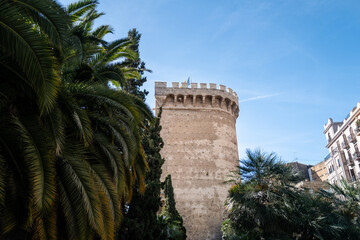Valencia, Spain - May 12 2023 :  Torres de Quart towers, historic city walls and prison stands tall on a bright blue sunny day surrounded by foliage and palm trees
