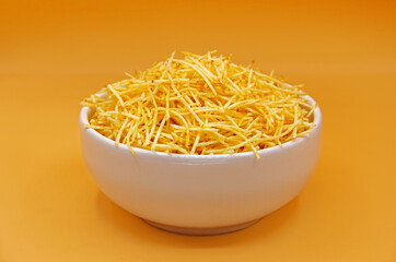 EXTRAFINE STRAW POTATOES IN BOWL WITH YELLOW ORANGE BACKGROUND