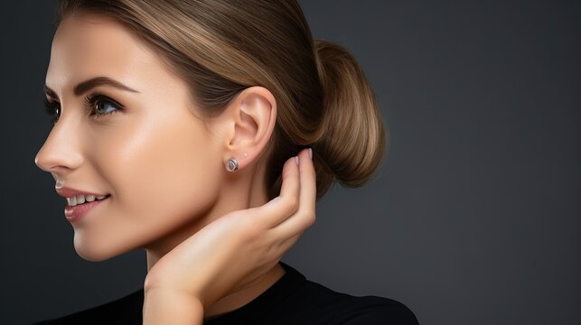Jewelry concept. Portrait of beautiful young female model wearing silver earrings. Close-up of woman with clean skin posing, in studio background.