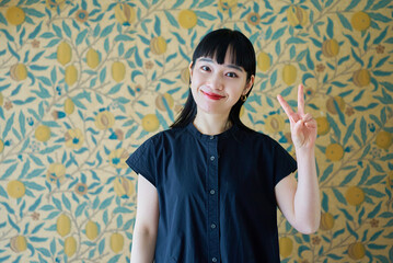 笑顔でピースサインをする若い女性