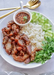 Fried pork with rice and vegetables on a white plate, thai food