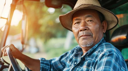 Foto op Aluminium Portrait of confident senior asian male farmer driving farm tractor in sunny day © evgenia_lo