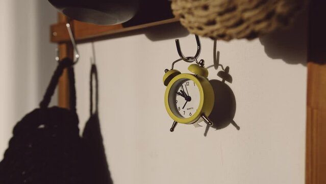 Timelapse quartz yellow clock goes fast. A period of time passes quickly, the sun's rays are in the background and the light changes direction.