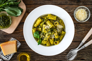 Pasta with basil pesto sauce on wooden table
