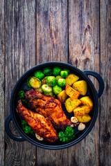Cooked rabbit thighs with potatoes and brussels sprout in frying pan
