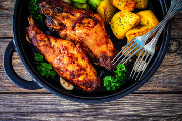 Cooked rabbit thighs with potatoes and brussels sprout in frying pan

