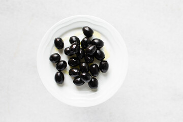 Black olives on a white plate, pitted Black olives on a ceramic plate