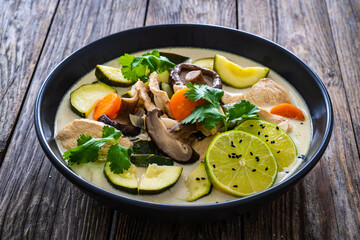 Tom Kha Gai soup - Thai soup with chicken breast nuggets and noodles on wooden table