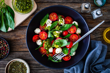 Caprese salad with pesto sauce on wooden board
