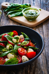 Caprese salad with pesto sauce on wooden board
