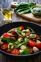 Caprese salad with pesto sauce on wooden board
