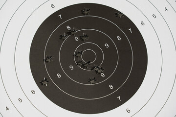 A paper target for shooting with holes from pistol bullets in the center, close-up photo.