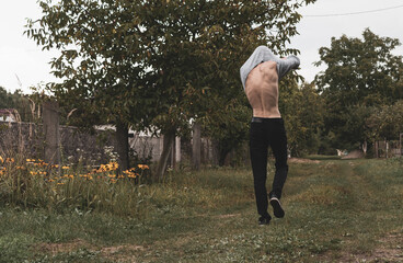 A young guy takes off his clothes while walking