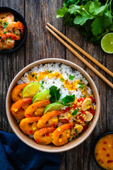 Fried shrimps with rice and vegetable salad in lunch box to go on wooden table

