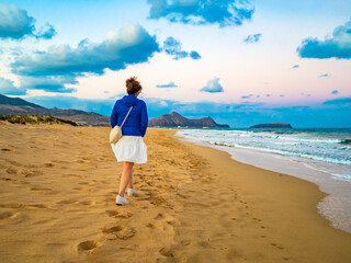 Mid-adult woman walking on beach at sunset
