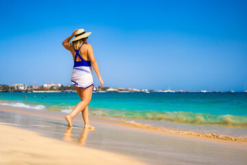 Beautiful woman walking on sunny beach Santa Maria, Sal Island, Cape Verde
