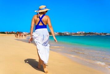 Fototapeta na wymiar Beautiful woman walking on sunny beach Santa Maria, Sal Island, Cape Verde 
