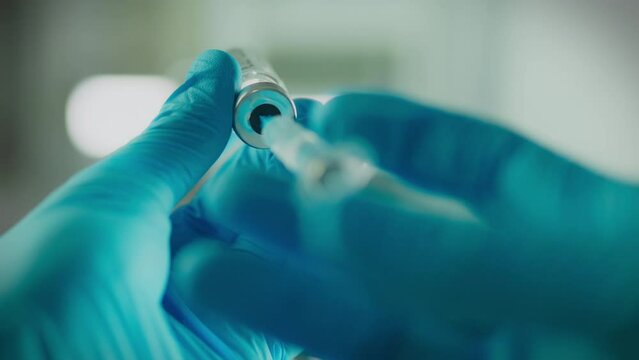 Patient. A doctor in glasses inserts syringe needle into a vial in a hospital. Camera in motion, an experienced professional prepares a liquid for an anesthesiologist using modern technology, medicine