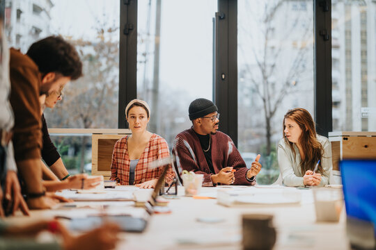 A group of diverse colleagues is actively participating in a brainstorming session in a brightly lit, contemporary office environment.
